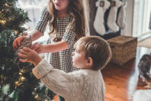siblings putting ornaments on tree